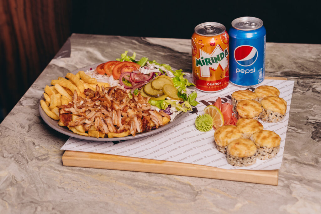 Uz dēlīša šķīvis ar kebabu un sushi ar dzērieniem