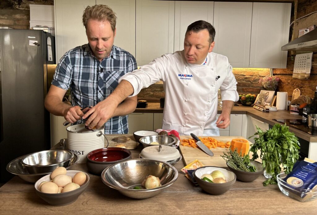 Šefpavārs palīdz viesim gatavot ēdienu