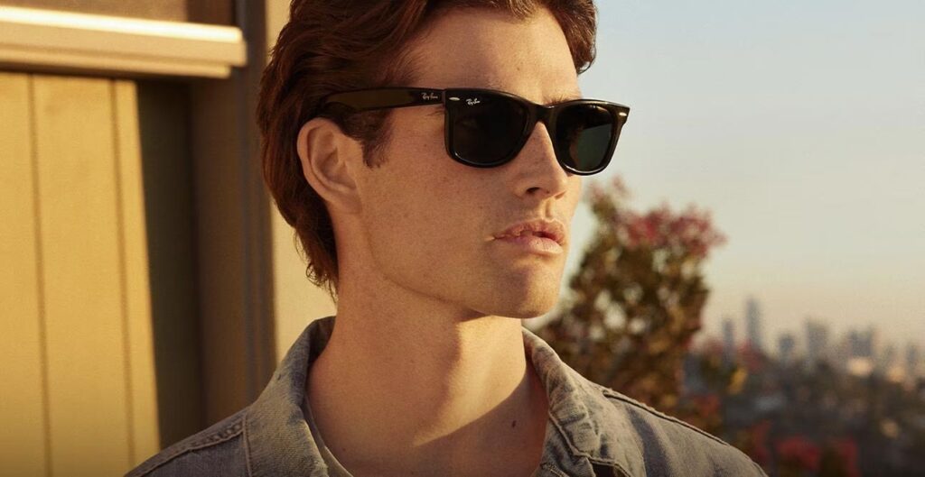 Vīrietis ar melnām ''Ray-Ban Wayfarer'' saulesbrillēm.