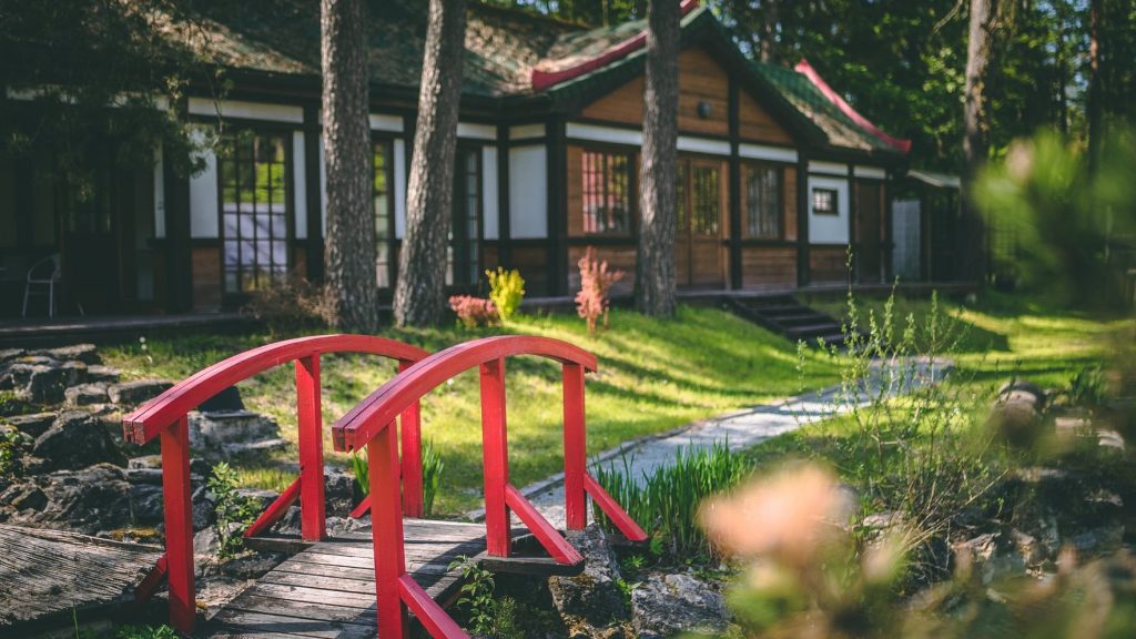 Bonsai parkā sarkans tiltiņš pāri mazai upei.