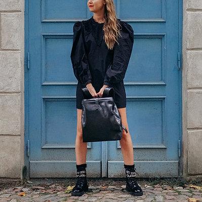 Sieviete rokās tur melnu ''RR Leather Accessories'' somu.