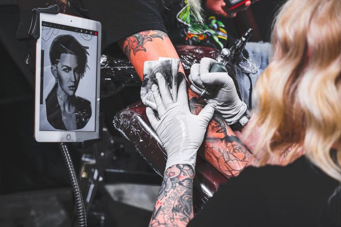 Tatoo saloni, sieviete tetovē vīrietim roku