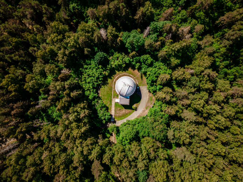 Baldones observatorija no augšas starp kokiem, meža vidū.