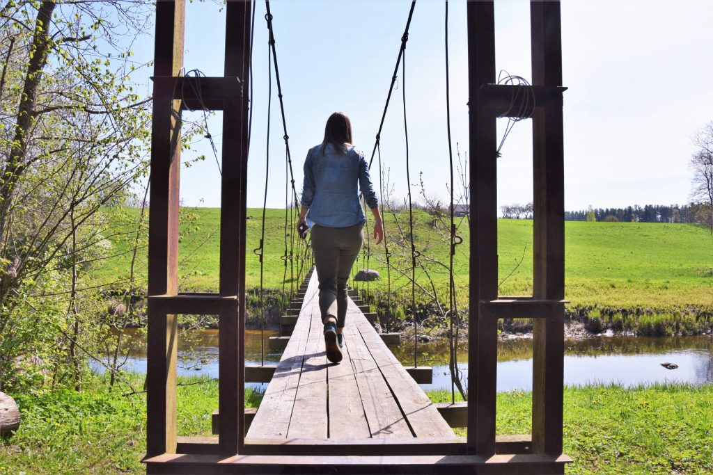 Sieviete iet pāru upei pa Eversmuižas Dabas taku