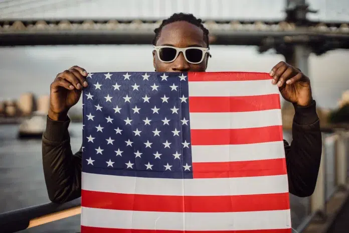 4. Jūlijs Amerikas Neatkarības svinības. Vīrietis tur ASV karogu.