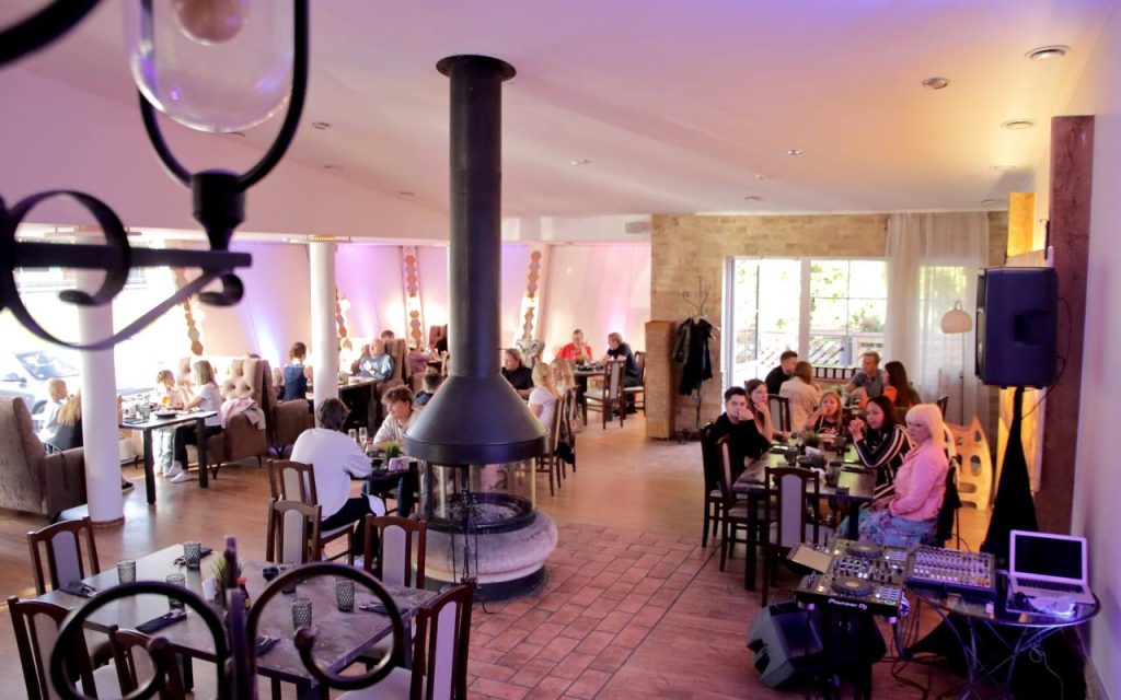 Cilvēki Kefējnīcā Milo, kas izgaismots ar zilām gaismām.