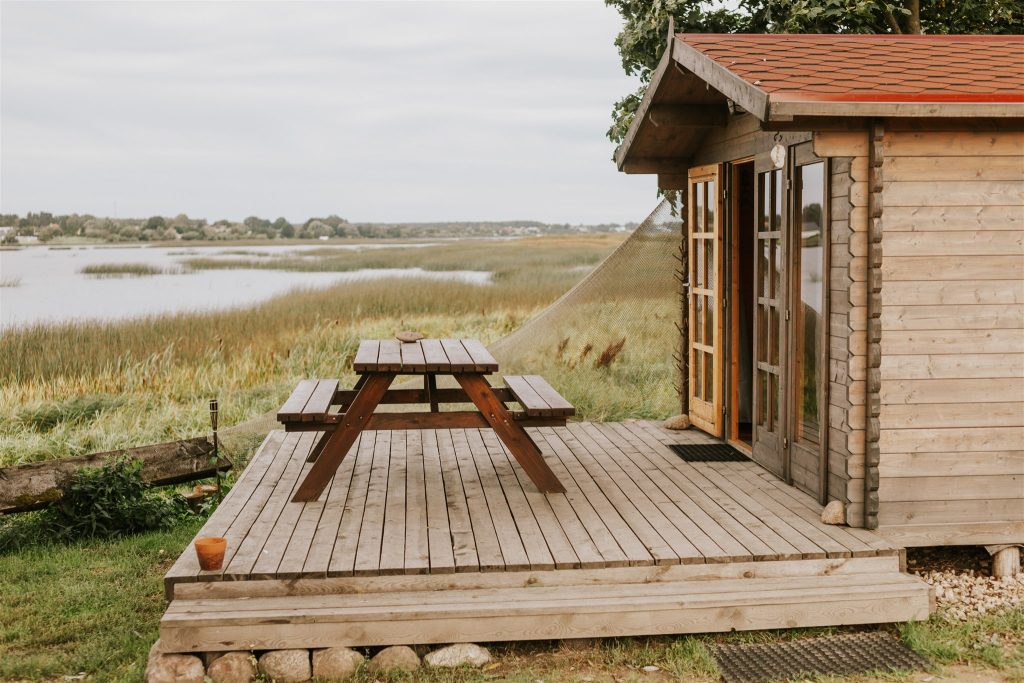 Kempings "Doles sala" koka mājiņa ar terasi un piknika galdu.