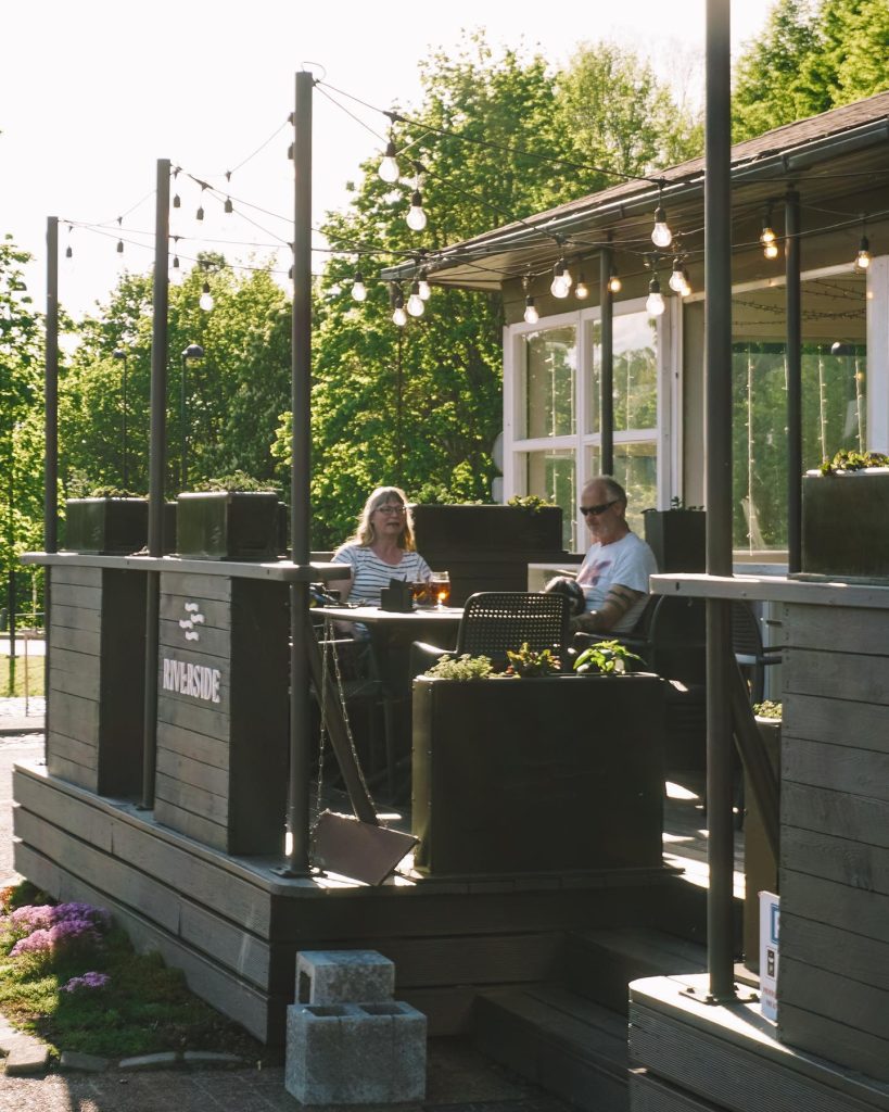 Sieviete sēž uz ''Cafè Riverside'' terases ārā