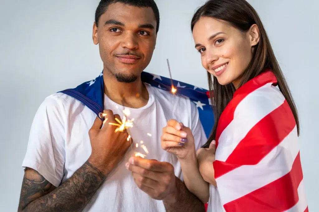 Amerikāņi svin neatkarības dienu. Sieviete un vīrietis aptinušies Amerikas karogā.