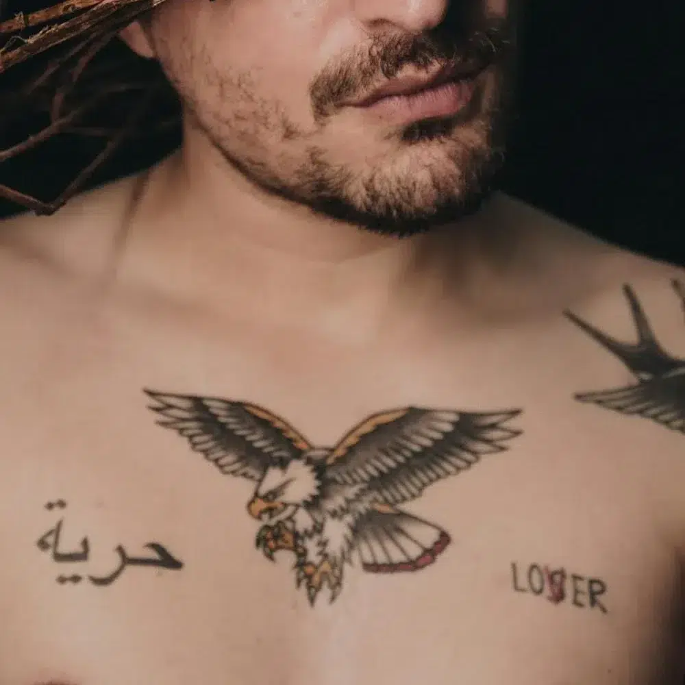 Vīrietim uz krūtīm mazs ērgļa tetovējums.