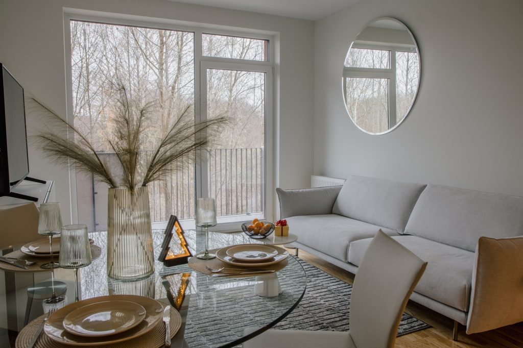 gaiša viesistaba ar stikla galdu un balkonu