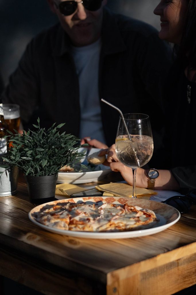 Kafējnīcas "Osteria" pica un vīns uz galda.