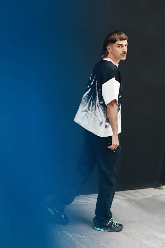 Jauns vīrietis ar īsu mullet frizūru skatās atpakaļ