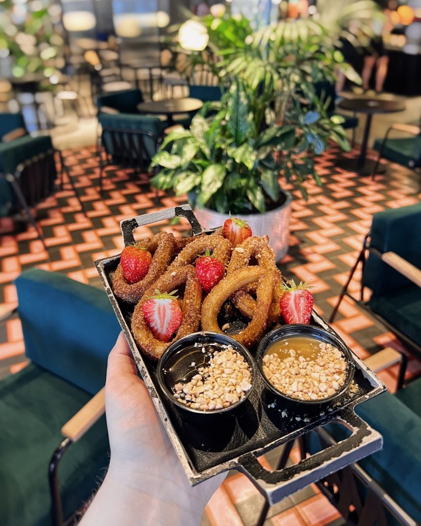Churros ar karameļu mērci uz melna šķīvja
