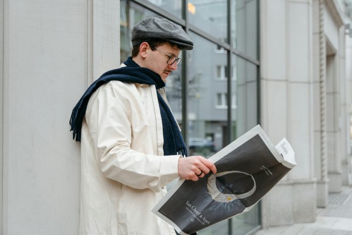 Vīrietis lasa žurnālu uz ielas