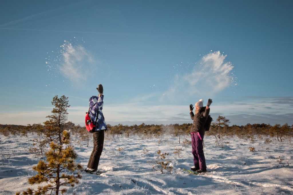 Divi cilvēki met gaisā sniegu Kangaru purvā ziemā