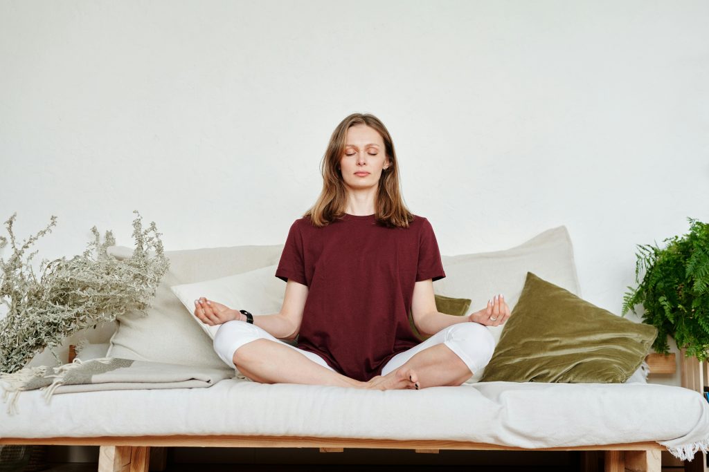 Sieviete meditē uz dīvāna visistabā
