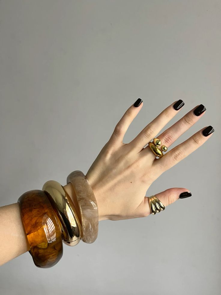 Sievietes roka ar trīs lielām aprocēm un gredzeniem