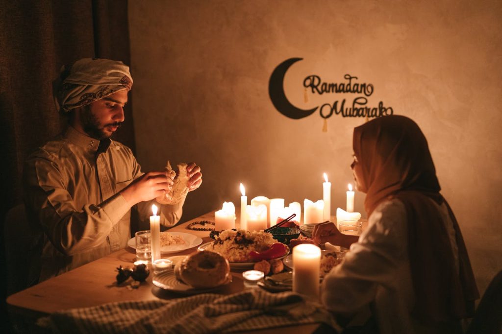 Vīrietis un sieviete sēž pie galda ar svecēm un ēd Ramadāna laikā