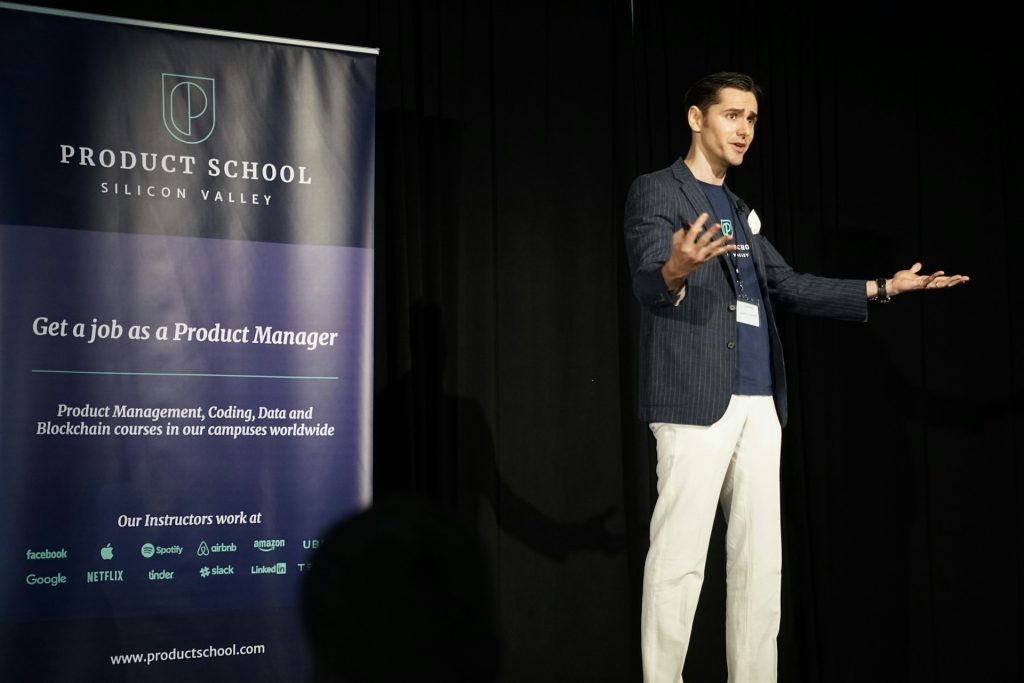 Vīrietis runā konferencē publikas priekšā