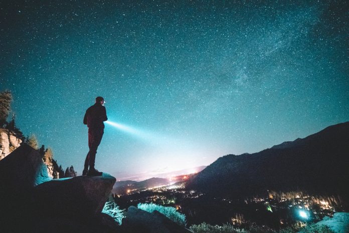 Vīrietis skatās debesīs uz zodiaka zvaigznājiem