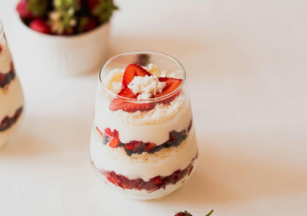 Kārtojums glāzē ar zemenēm un putukrējumu