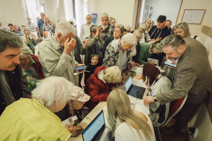 Cilvēki stāv rindās lai parakstītos par OIK atgūšanu